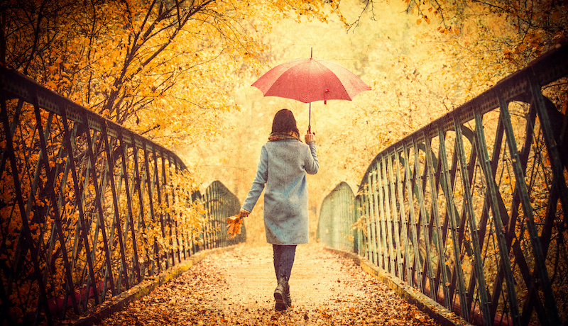 A young woman walking among the golden leaves of autumn